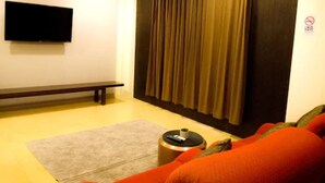 A living room with a sofa, a bench, a television, and a curtain. - NIM SEE SENG Hotel (Chiang Mai)