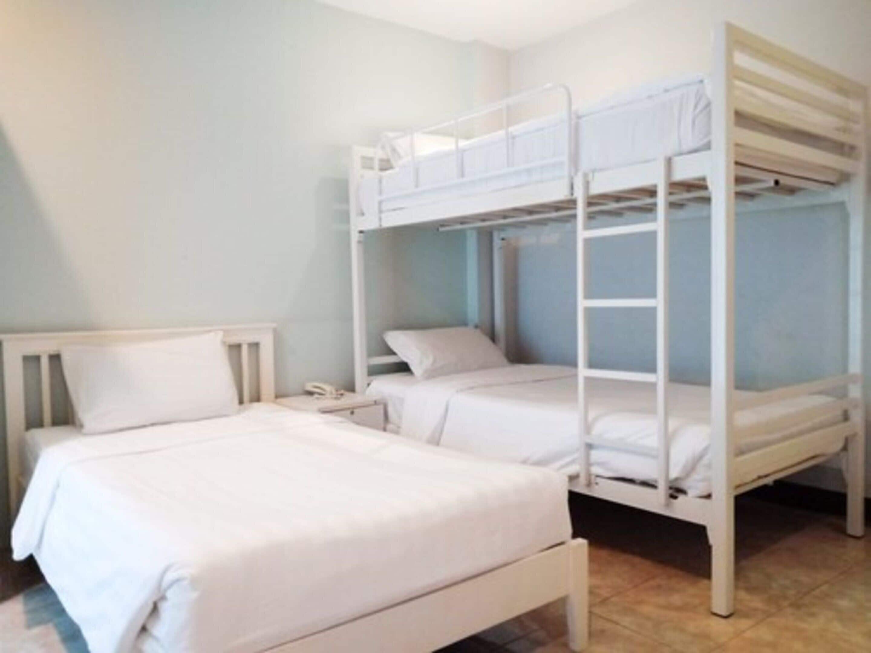 A room with two bunk beds, a bedside table with a phone, and a window with curtains.