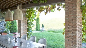 An outdoor patio with a stone floor, a wooden ceiling, and a brick column.