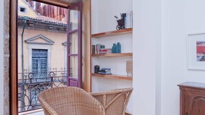 A balcony with wicker chairs, a wooden bookshelf, and a small cabinet. - Flowerstreet54 - Romantic Apartment at Downtown Center (Porto)