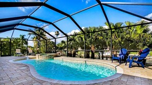 Una piscina interior con techo de cristal, rodeada de palmeras y sillas azules.
