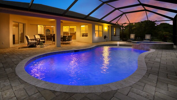 Una piscina con techo de vidrio, mobiliario exterior y zona de patio.