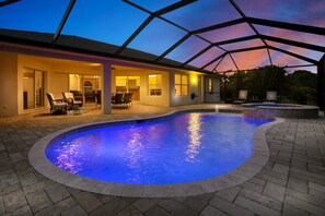 Une piscine dotée d’un toit en verre, d’un espace salon extérieur et d’un patio.