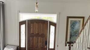 A spacious entryway with a wooden door, a staircase with white balusters, and a framed painting on the wall. - Spacious Countryside Home Near Sanford - 3BR,2.5BA (Sanford)