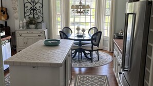 A kitchen with a central island, dining table, and chairs, with a refrigerator and cabinets on one side. - Spacious Countryside Home Near Sanford - 3BR,2.5BA (Sanford)