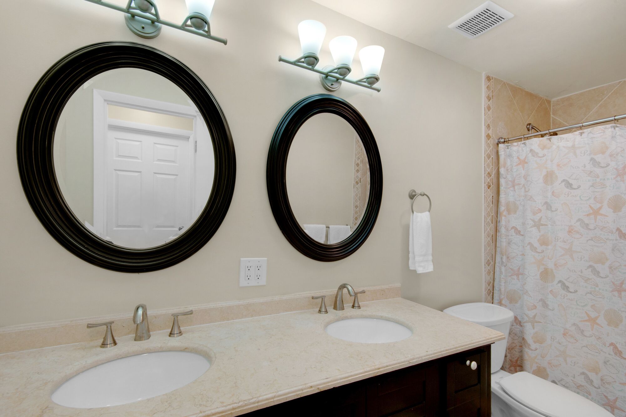 A bathroom with two sinks, a shower, and two large mirrors.