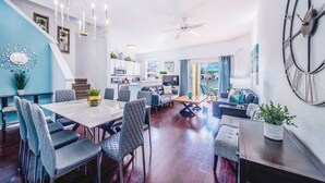 A modern living room with a dining area, a staircase, and a kitchen in the background. - TROPICAL RESORT! 3 Pools, Lazy River, Water Slide +more!  4 BED/3 BATH (Davenport)