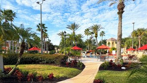 A resort with a pool, outdoor seating, palm trees, and a clear sky. - TROPICAL RESORT! 3 Pools, Lazy River, Water Slide +more!  4 BED/3 BATH (Davenport)
