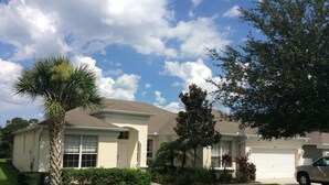A two-story house with a garage, a well-maintained lawn, and a palm tree. - 5*Luxury Villa 6BR,4BA 3Ensuits /Pool facing SE/10mins to Disney parks,free Wifi (Kissimmee)