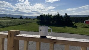 Une clôture en bois, avec une tasse blanche sur laquelle on peut lire « Ports maritimes de l’Acadie », par une journée ensoleillée.