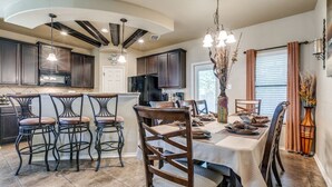 A modern kitchen with dark wood cabinets, a central island, and bar stools. - Beautiful & Cozy, BMT Friendly near SeaWorld 3mi/Six Flags 14mi/Lackland 8mi (San Antonio)