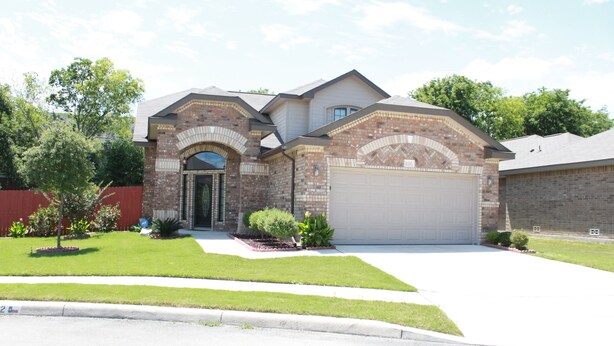 A two-story house with a brick facade, a garage, and a well-maintained lawn. - Beautiful & Cozy, BMT Friendly near SeaWorld 3mi/Six Flags 14mi/Lackland 8mi (San Antonio)