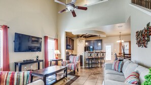 A spacious living room with a sofa, a coffee table, and a TV. There is a kitchen area with a dining table and chairs. - Beautiful & Cozy, BMT Friendly near SeaWorld 3mi/Six Flags 14mi/Lackland 8mi (San Antonio)