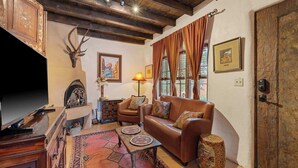 A cozy living room with a fireplace, leather sofa, patterned rug, and wooden decor.