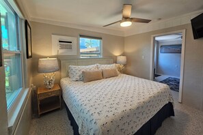 Una camera da letto con un letto, due lampade da comodino, una ventola a soffitto e una finestra.
