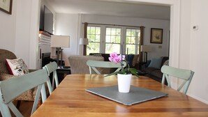 A dining area with a wooden table, chairs, and a potted orchid.
