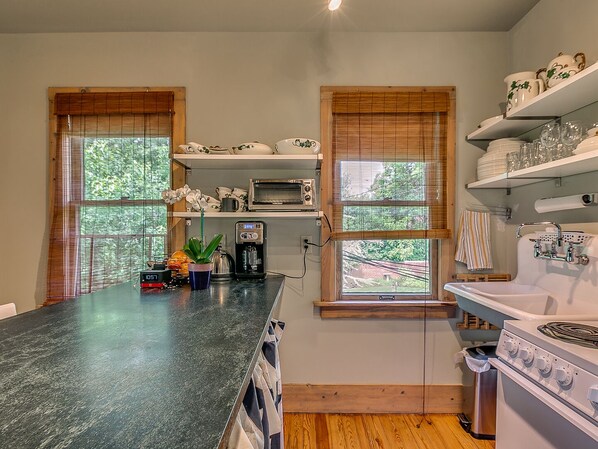 Una cocina con encimera de granito, cafetera, tostadora y estufa.