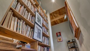 Una biblioteca con estanterías de madera llenas de libros y marcos con fotografías.
