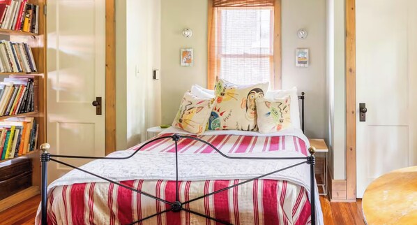 Un dormitorio con cama, una estantería, una ventana y un reloj de pared.