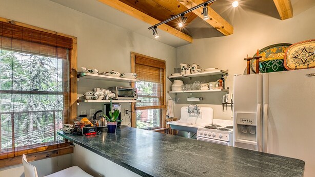 Una cocina con encimera de granito, electrodomésticos blancos y vigas de madera en el techo.