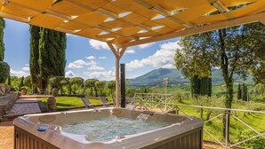 Un jacuzzi bajo una pérgola con una vista panorámica de montañas y árboles.