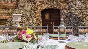 Mesa lista para comer con un muro de piedra y una puerta de madera al fondo.