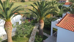 A residential area with palm trees, a stone pathway, and houses with red-tiled roofs. - Houdis House - Beautiful House for relaxing in garden with Pool. (Paralio Astros)