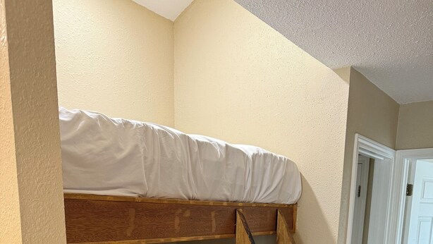 A bunk bed with a wooden ladder, beige walls, and a tiled floor. - River Front property (Seguin)