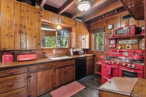 A wooden cabin kitchen with a sink, stove, and a microwave on a shelf. - Rustic 1926 Lodge Style Cabin Near Lake + Spa + 3 Bonus Rooms (Lake Arrowhead)