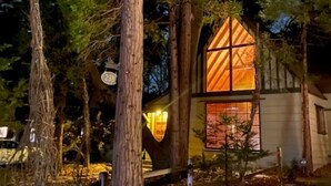 A cabin with a large window and a wooden fence.