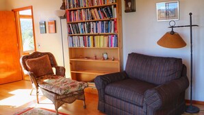 Una sala de estar acogedora con una estantería, un sillón estampado, un sofá a rayas y una lámpara de pie.