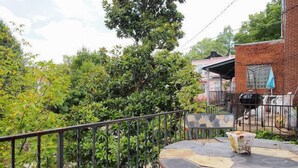 A round metal table with a white object on it, surrounded by greenery and a metal fence. - Artsy Homey Rowhouse, 3bdrm & office, quiet urban area, free parking, fast WiFi (Baltimore)