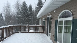 Una terraza cubierta de nieve con barandilla de madera y puerta de vidrio.