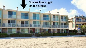 A beachfront hotel with multiple balconies, a sandy beach in front, and a clear sky. - On the Beach!!  Perfect for Families.  Right on the Water (San Diego)