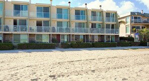 A beachfront hotel with multiple balconies, a sandy beach in front, and a clear sky. - On the Beach!! Perfect for Families. Right on the Water (San Diego)