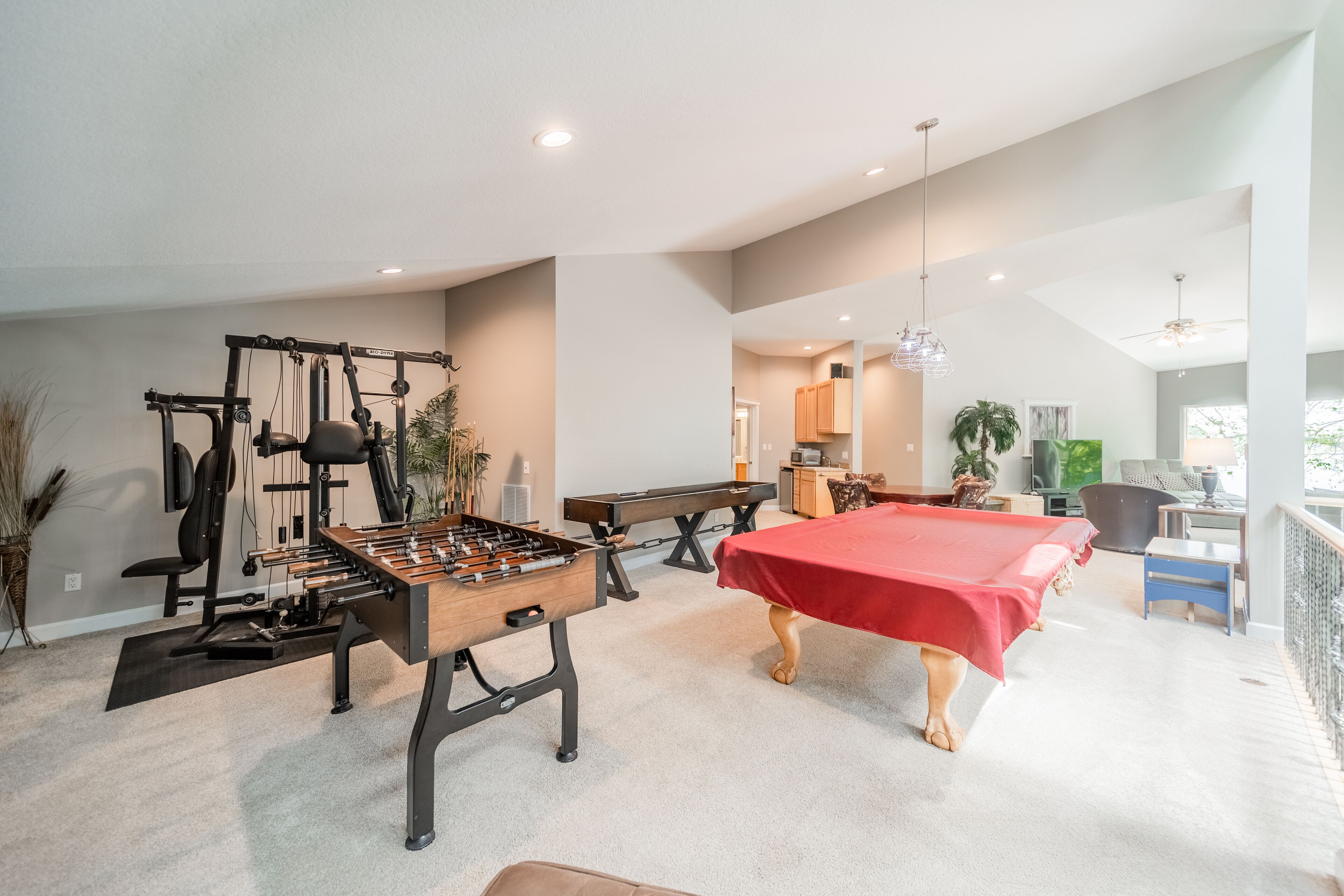 A spacious living area with a foosball table, a pool table, and exercise equipment.