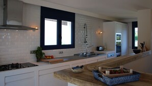 A modern kitchen with white cabinets, a gas stove, a sink, and a window with a view. - Modern Seaview Villa With Infinity-Pool (Palamos)
