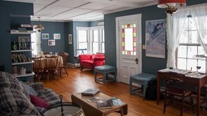 A living room with a dining area, a red armchair, a blue bench, and a wooden coffee table. - Fall Colors Await-Book Early Escape to Crisp Mountain Air-Family Fun Pets ok (Franconia)