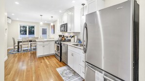 Una cocina moderna con armarios blancos, electrodomésticos de acero inoxidable y una zona de comedor de madera.