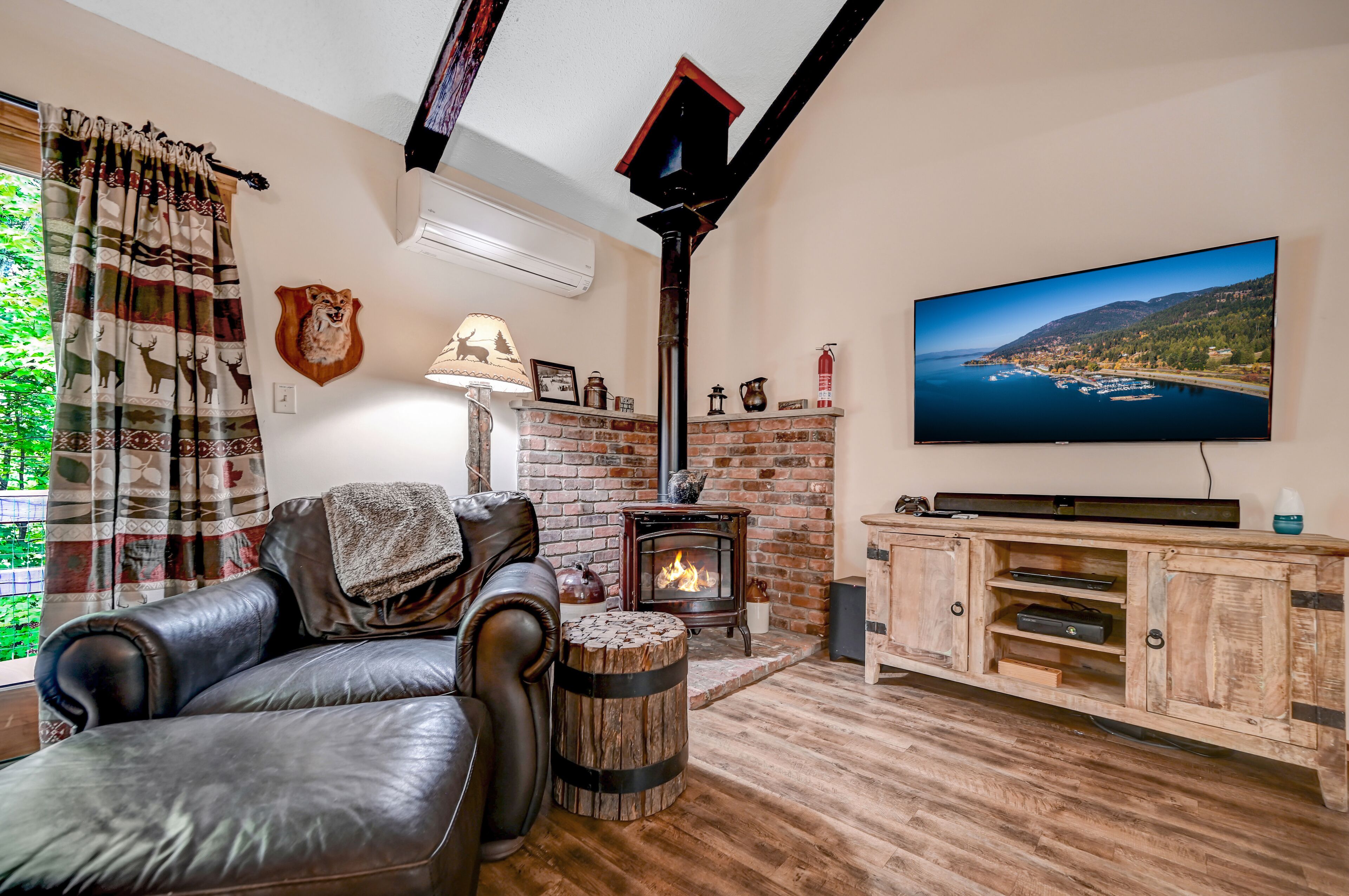 A cozy living room with a fireplace, leather sofa, and a TV mounted on the wall.