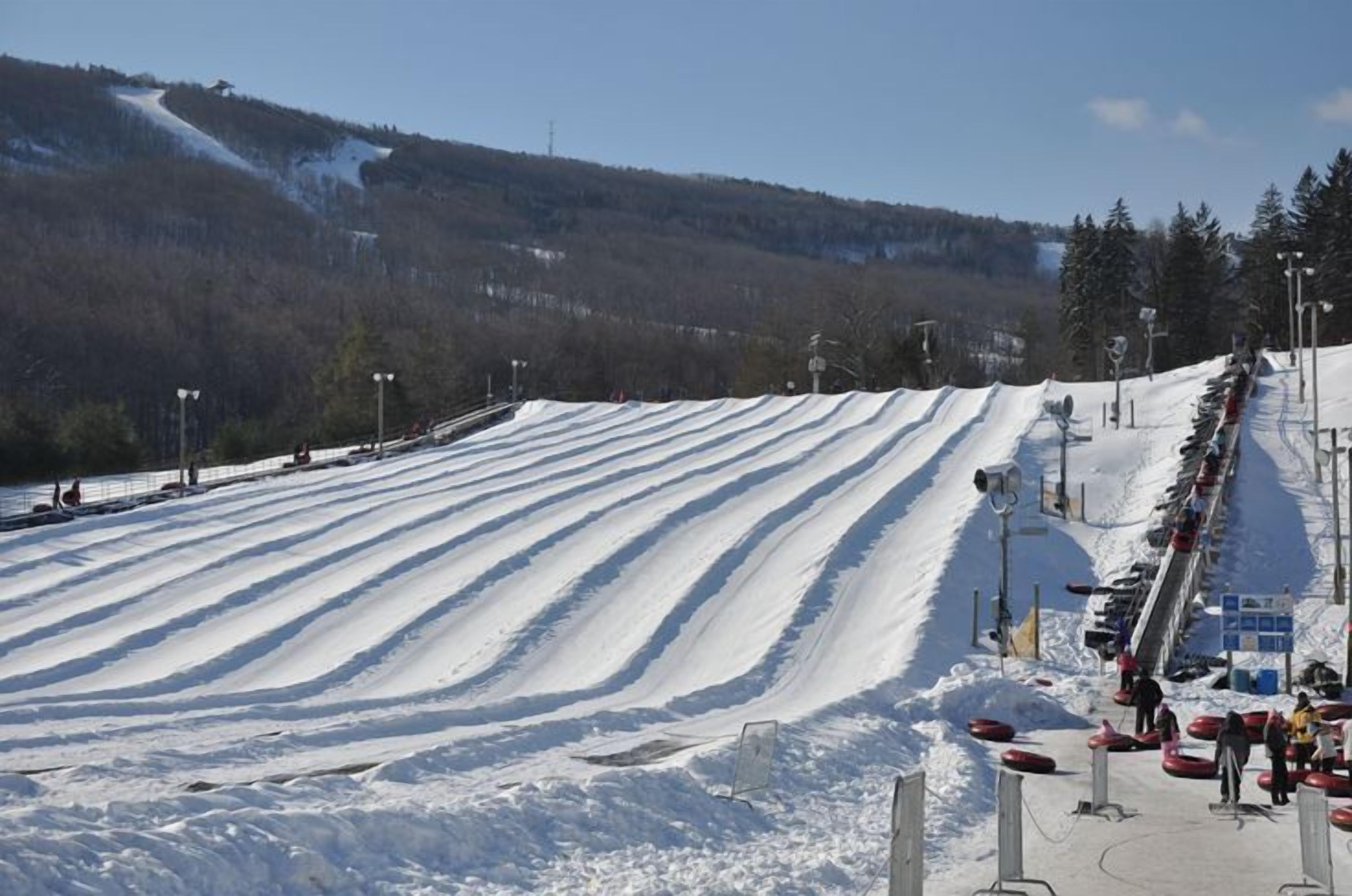 A snow-covered ski slope with marked lanes and a queue of people waiting for their turn.