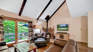 A cozy living room with a fireplace, leather furniture, and a large window overlooking greenery. - Camelback,Aquatopia/Camelbeach Waterparks,Pool,Tennis,Paintball,Zip-Line,Jacuzzi (Tannersville)