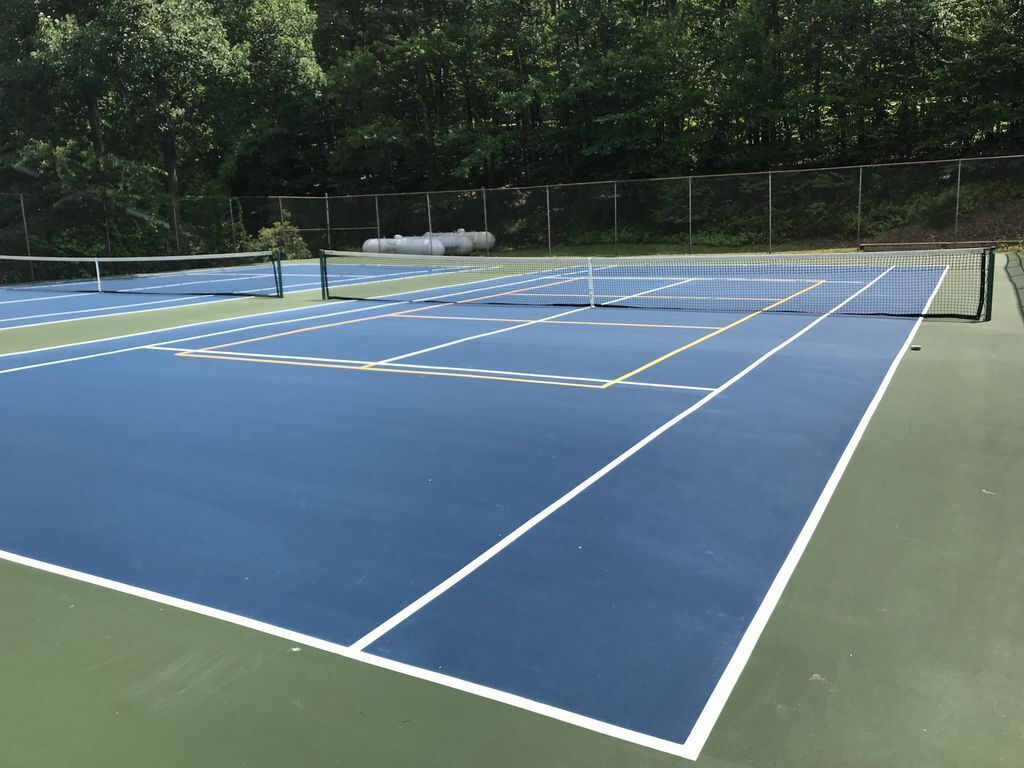 Un court de tennis avec un filet, entouré d’arbres.