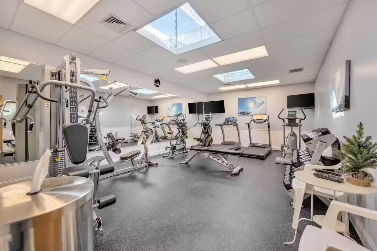 A gym with various exercise equipment, including treadmills, stationary bikes, and weight machines.