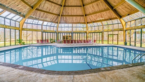 A large indoor swimming pool with a wooden roof and glass walls. - Camelback,Aquatopia/Camelbeach Waterparks,Pool,Tennis,Paintball,Zip-Line,Jacuzzi (Tannersville)