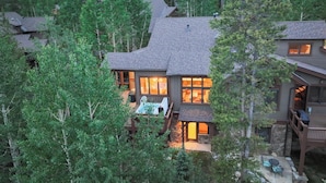 A multi-story house with a stone foundation, large windows, and a deck.