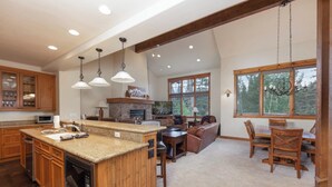 A spacious kitchen with granite countertops, wooden cabinets, and a stone fireplace.