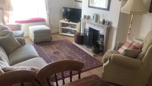 Uma sala de estar com sofá, poltrona, mesa de madeira e lareira.
