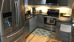 A modern kitchen with stainless steel appliances, grey cabinets, a microwave, and a coffee maker. - Modern house, Hot Tube, lakes, pools, water parks, Ski, tennis A/C Free WiFi (Albrightsville)