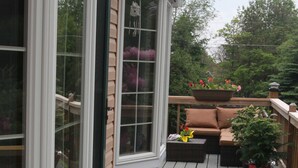 A wooden deck with a sliding glass door, a cushioned outdoor seating area, and a potted plant. - Modern house, Hot Tube, lakes, pools, water parks, Ski, tennis A/C Free WiFi (Albrightsville)